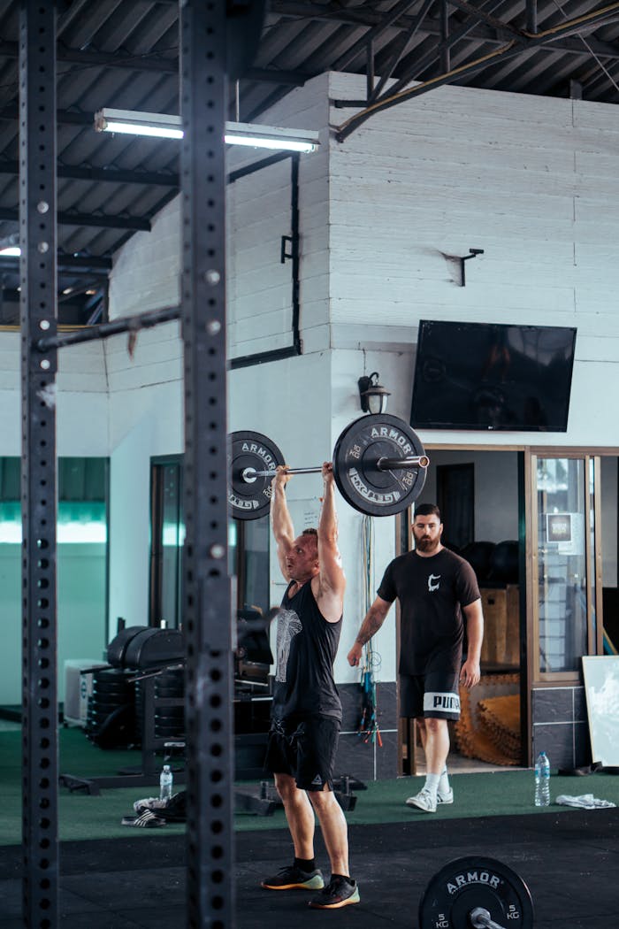 Offerings A man lifting a barbell in a modern gym with gym equipment in the background.