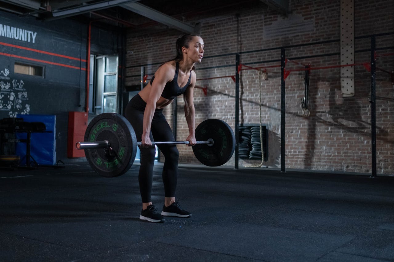Mastering the First Impression: Your intriguing post title goes here A determined woman performing deadlifts in a modern gym environment, showcasing strength and fitness.